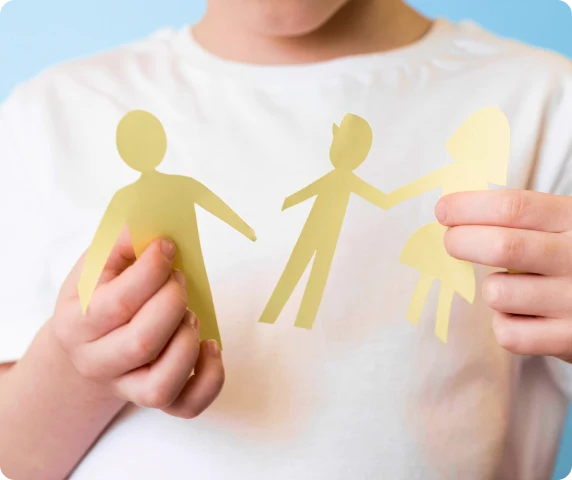 Et barn i en hvit skjorte holder et avrevet papirutklipp av en familie, som symboliserer separasjon. Sakkyndig vitnetjenester på barnes sakkyndig.no.