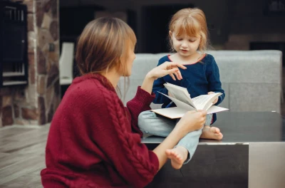 Mor og datter deltar i et læringsøyeblikk med en bok som symboliserer barnerådgivning og hvordan det fungerer i barns utvikling.