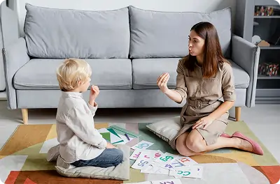 Bildet viser en gutt som øver på tale med terapeuten sin.