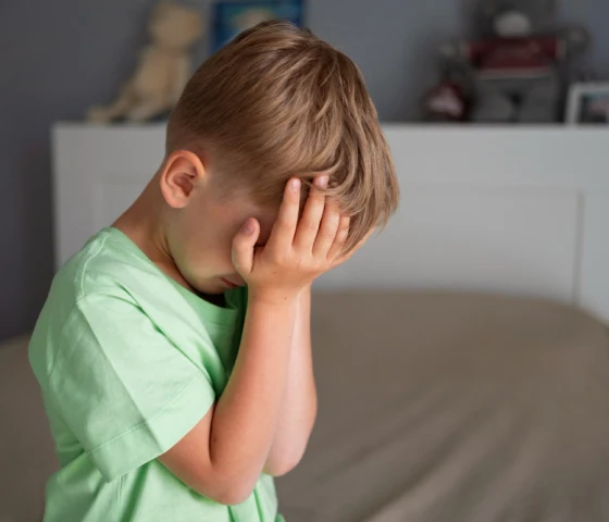 Stresset barn med hendene foran ansiktet, et bilde som illustrerer hvordan barn opplever psykisk stress og behovet for mestringsferdigheter.