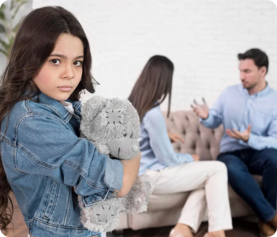 Et barn holder en bamse og ser trist ut mens to voksne krangler i bakgrunnen, noe som illustrerer utfordringer i barnefordelingssaker og betydningen av å ivareta barnets beste.