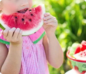 Barn som spiser vannmelon ute i naturen – et symbolsk bilde relatert til spiseforstyrrelser hos barn.