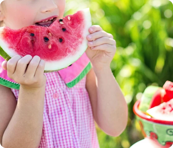 Barn som spiser vannmelon ute i naturen – et symbolsk bilde relatert til spiseforstyrrelser hos barn.