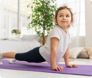 Et lite barn gjør en strekkøvelse på en yogamatte hjemme, som illustrerer temaet Barn og fysisk aktivitet: En viktig gave for livet.