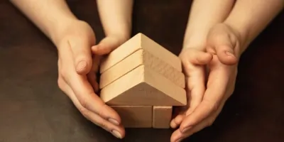 Hender som forsiktig holder et trehus, symboliserer beskyttelse, omsorg og stabilitet. Forhold sakkyndig vurderingstjenester etter barnevernloven på barnesakkyndig.no.