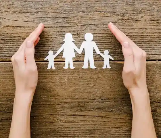 Hender som rammer inn en papirutklippsfamilie, som symboliserer beskyttelse og omsorg. Relatert om barnesakkyndig.no